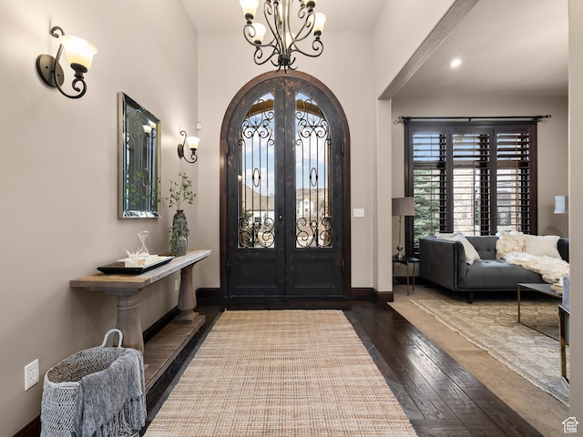 foyer entrance featuring dark hardwood / wood-style flooring, a chandelier, and french doors