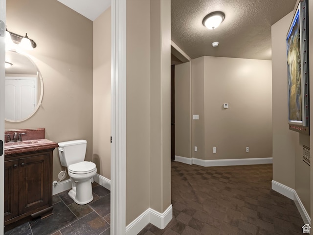bathroom with toilet, vanity, and a textured ceiling