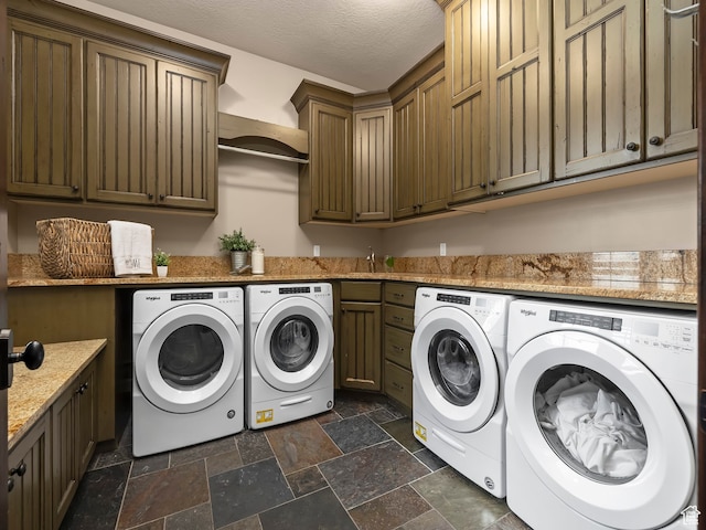 laundry area with washer and clothes dryer, sink, a textured ceiling, and cabinets