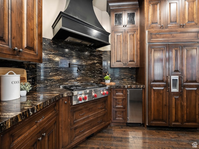 kitchen featuring dark wood-type flooring, backsplash, stainless steel gas cooktop, and custom range hood