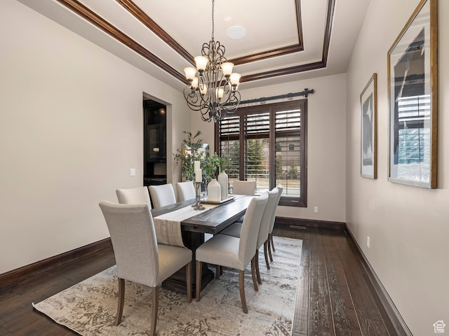 dining area featuring a raised ceiling, dark hardwood / wood-style floors, a chandelier, and ornamental molding