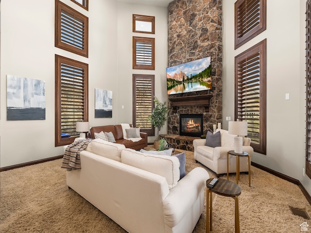 living room featuring a towering ceiling, a stone fireplace, and carpet flooring