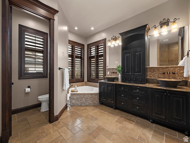 bathroom featuring toilet, vanity, and a relaxing tiled tub