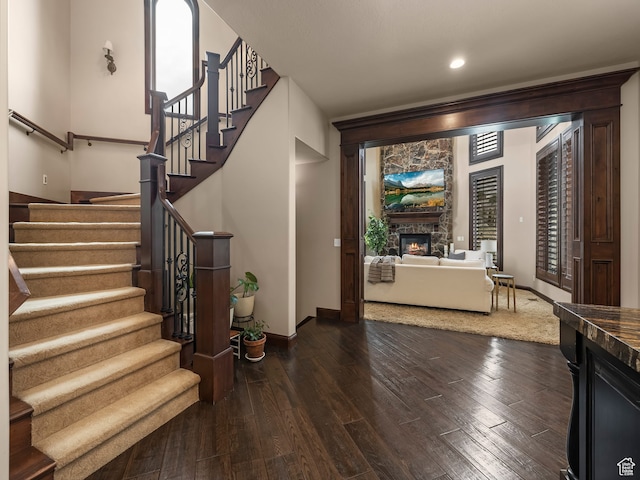 entryway with dark hardwood / wood-style floors and a stone fireplace