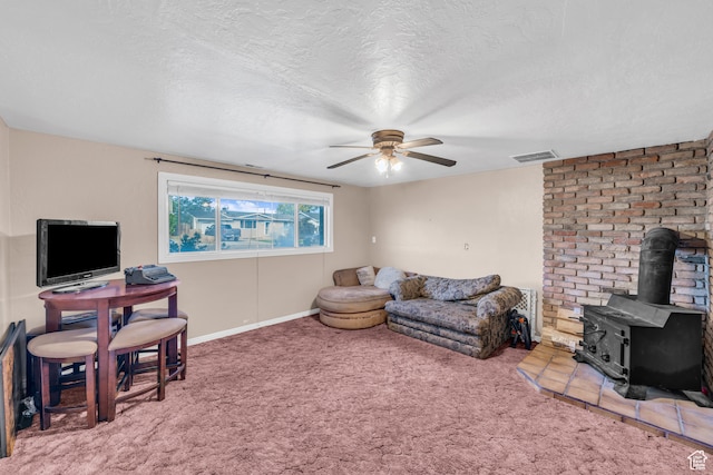 carpeted living room featuring ceiling fan, a wood stove, and a textured ceiling