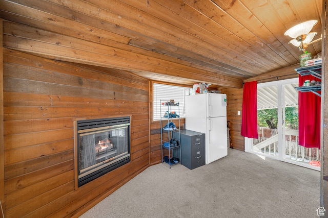 interior space with wood walls, carpet flooring, wooden ceiling, lofted ceiling, and white fridge
