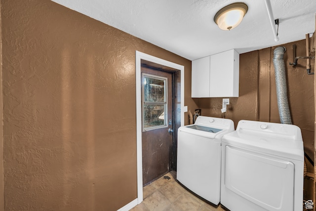 laundry area with a textured ceiling, washing machine and dryer, light tile patterned floors, and cabinets
