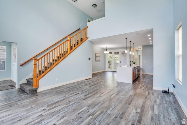 4489 W Milford Dr, South Jordan, UT 84009 - unfurnished living room featuring stairway, baseboards, a high ceiling, and wood finished floors