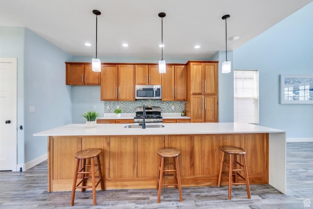 4489 W Milford Dr, South Jordan, UT 84009 - kitchen featuring decorative backsplash, light countertops, brown cabinets, a sink, and appliances with stainless steel finishes