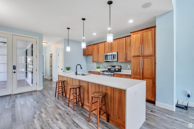 4489 W Milford Dr, South Jordan, UT 84009 - kitchen featuring brown cabinets, appliances with stainless steel finishes, a sink, light countertops, and light wood-type flooring