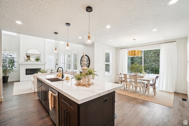 kitchen featuring a sink, a textured ceiling, dark brown cabinets, and dishwasher