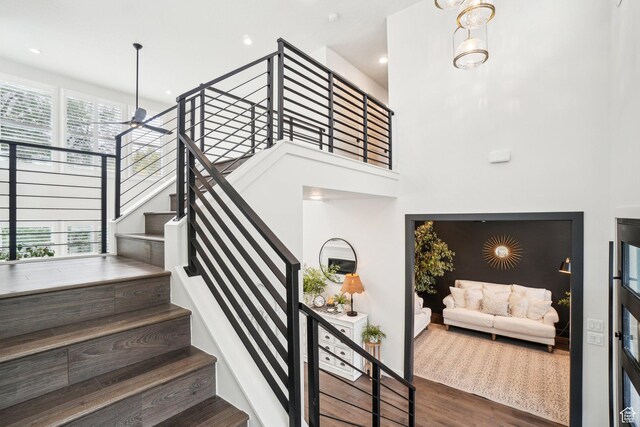 stairway featuring recessed lighting, a high ceiling, and wood finished floors