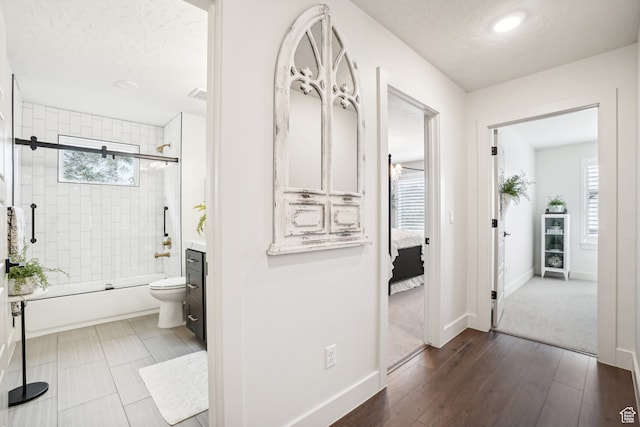 bathroom with baseboards, toilet, plenty of natural light, and shower / bath combination with glass door