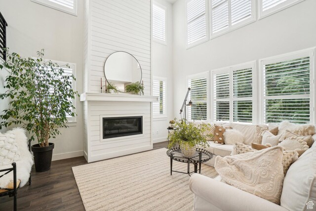 living area with a healthy amount of sunlight, dark wood-type flooring, and a high ceiling