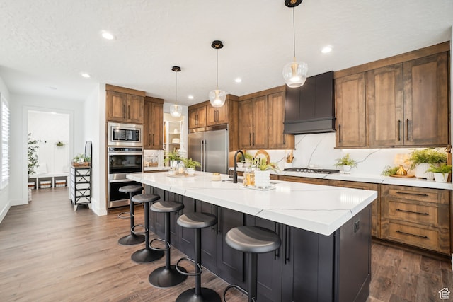 kitchen featuring built in appliances, recessed lighting, brown cabinetry, a sink, and dark wood-style floors