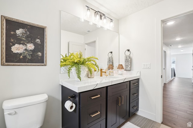 bathroom featuring vanity, toilet, wood finished floors, and baseboards