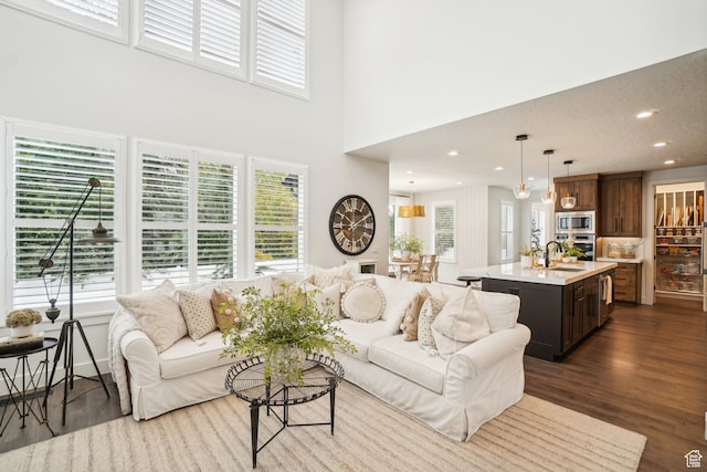 living area featuring dark wood-type flooring, a towering ceiling, and recessed lighting