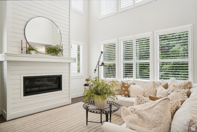living room with a healthy amount of sunlight, wood finished floors, a high ceiling, and a glass covered fireplace