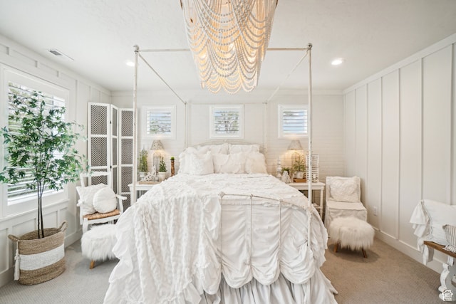 carpeted bedroom with visible vents, a decorative wall, and recessed lighting