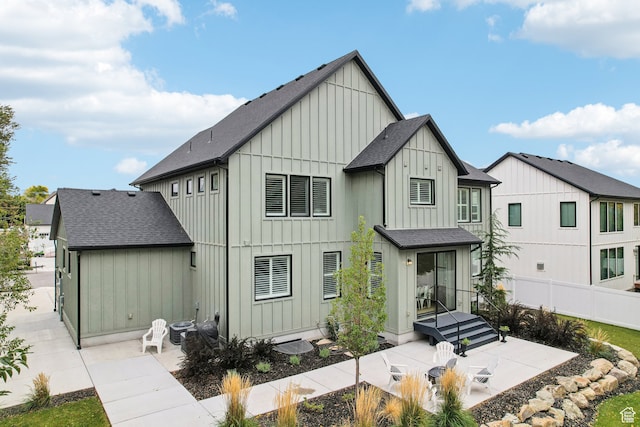 view of front facade featuring board and batten siding, fence, a patio area, central AC unit, and roof with shingles