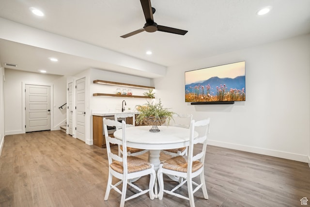 dining space featuring wet bar, recessed lighting, a ceiling fan, baseboards, and light wood-style floors