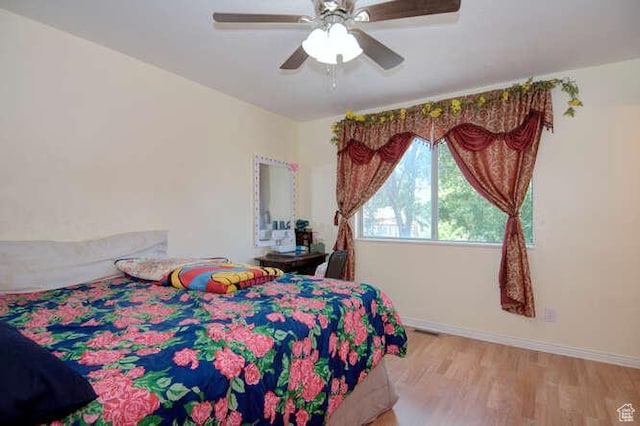 bedroom featuring baseboards, light wood finished floors, and a ceiling fan