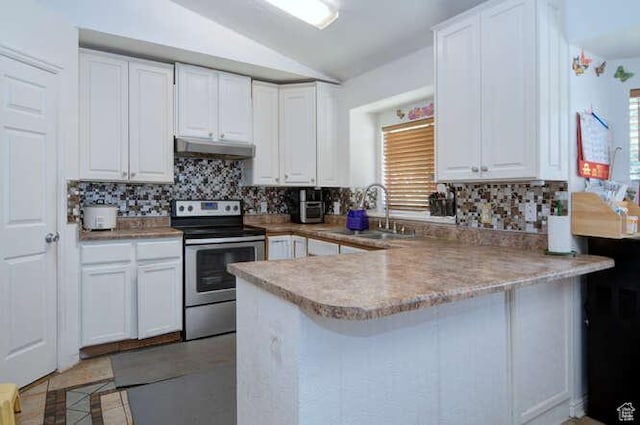 kitchen featuring stainless steel range with electric cooktop, under cabinet range hood, a sink, vaulted ceiling, and a peninsula