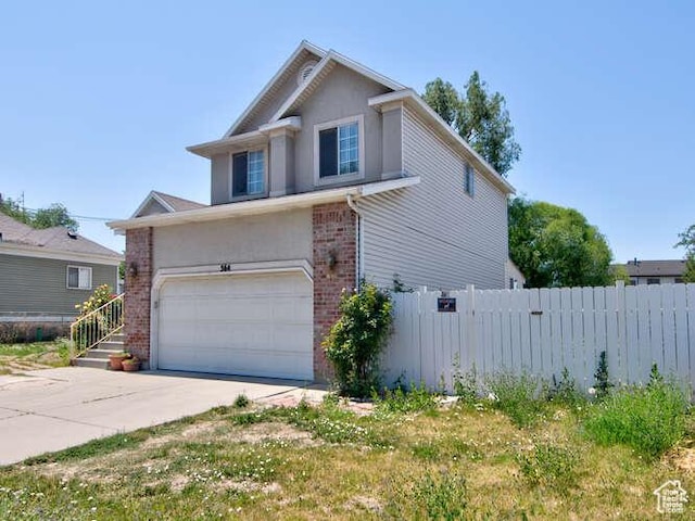 view of side of home featuring fence, brick siding, concrete driveway, an attached garage, and stucco siding