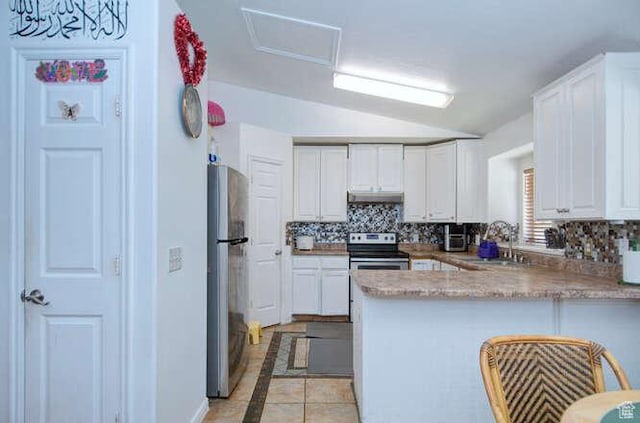kitchen featuring appliances with stainless steel finishes, inlaid floor details, vaulted ceiling, a peninsula, and backsplash