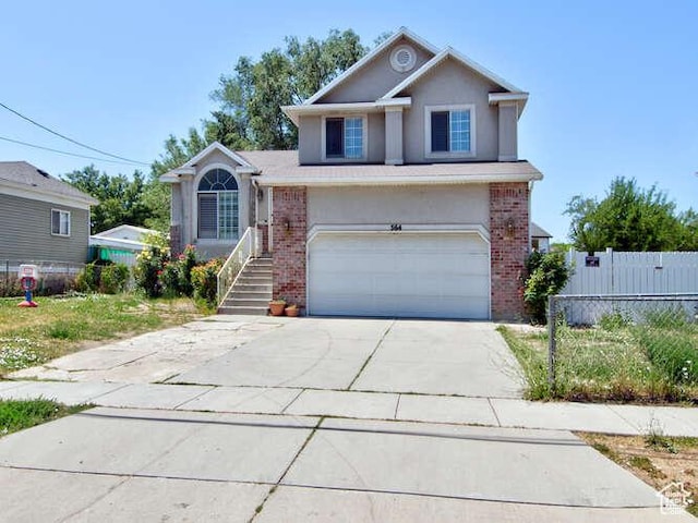 traditional-style house with brick siding, stucco siding, a garage, concrete driveway, and fence