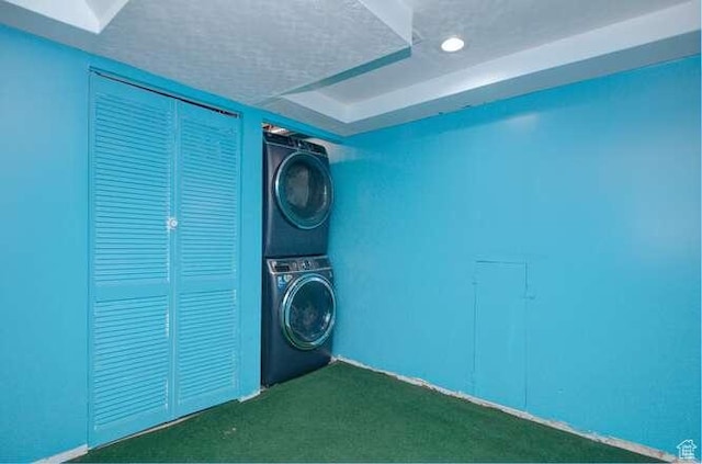 laundry area with stacked washer and clothes dryer and dark carpet