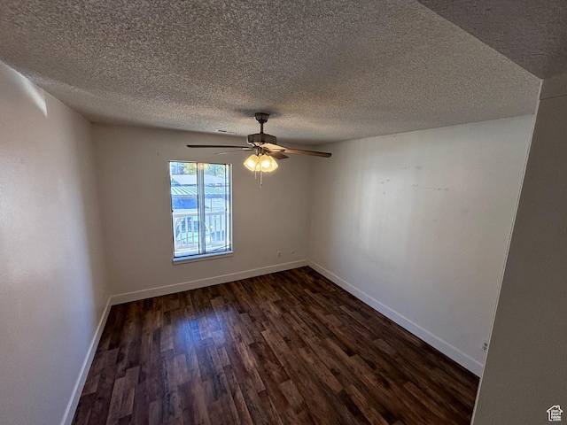 spare room featuring baseboards, ceiling fan, dark wood finished floors, and a textured ceiling