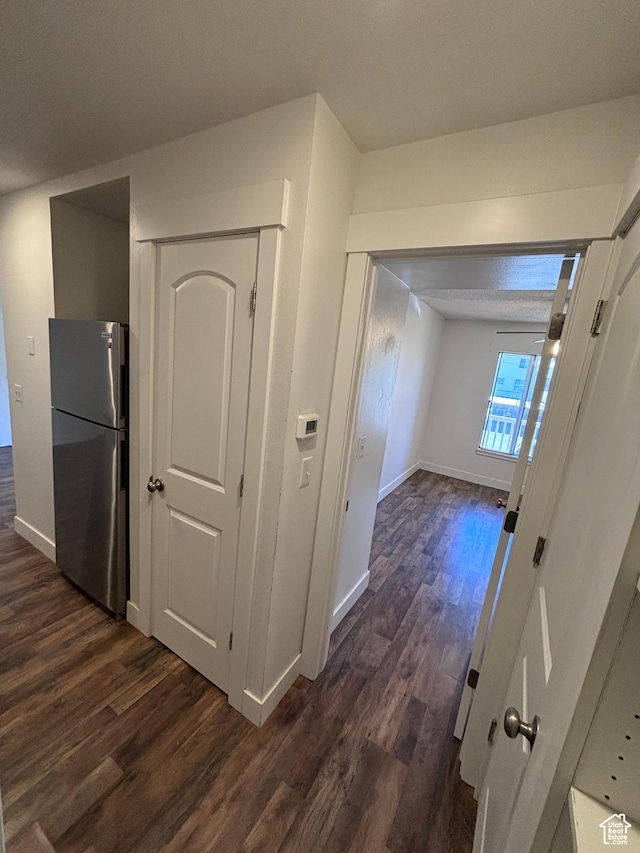 corridor featuring baseboards and dark wood-type flooring