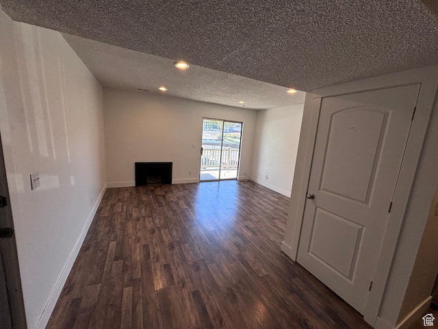 unfurnished living room featuring baseboards, a textured ceiling, dark wood-style flooring, and a fireplace