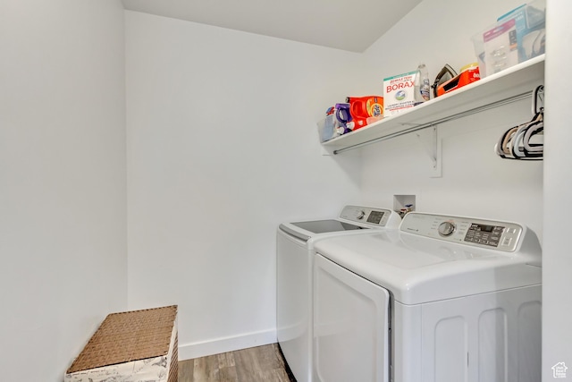 laundry area with baseboards, laundry area, light wood finished floors, and washer and clothes dryer