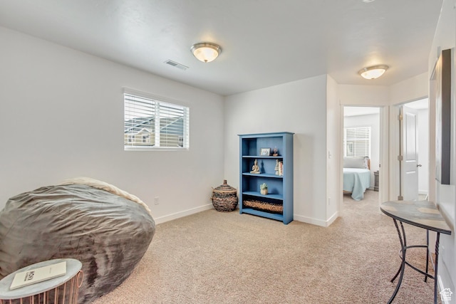 sitting room featuring visible vents, baseboards, and light carpet