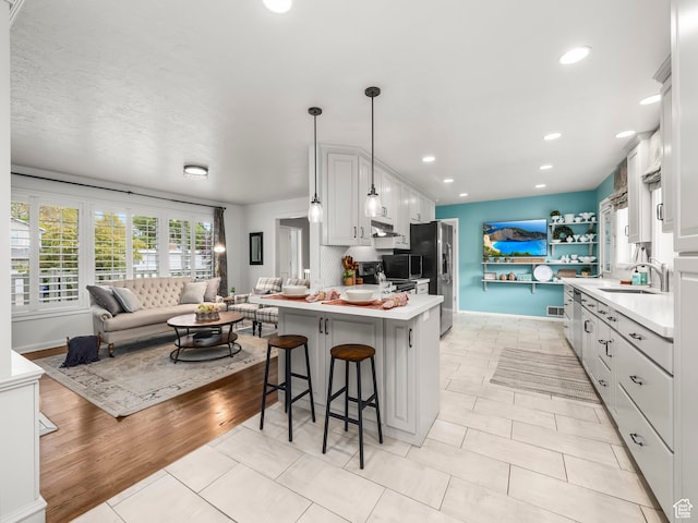 1975 E Gunderson Ln S, Holladay, UT 84124 - kitchen featuring kitchen peninsula, decorative light fixtures, white cabinets, a breakfast bar, and stainless steel refrigerator with ice dispenser