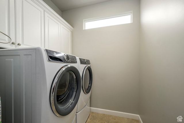 laundry area featuring baseboards, cabinet space, and separate washer and dryer