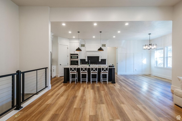 104 S 950 E, Hyde Park, UT 84318 - kitchen with a breakfast bar area, light wood-style floors, white cabinets, a large island, and a chandelier