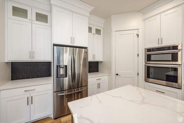 104 S 950 E, Hyde Park, UT 84318 - kitchen featuring appliances with stainless steel finishes, glass insert cabinets, decorative backsplash, and white cabinetry