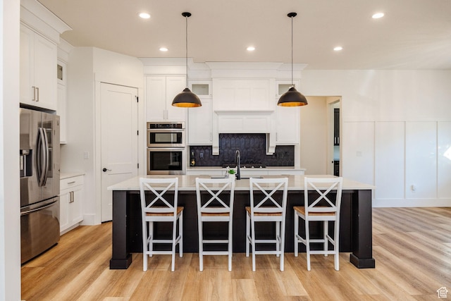 104 S 950 E, Hyde Park, UT 84318 - kitchen featuring appliances with stainless steel finishes, light wood-style floors, light countertops, backsplash, and a large island