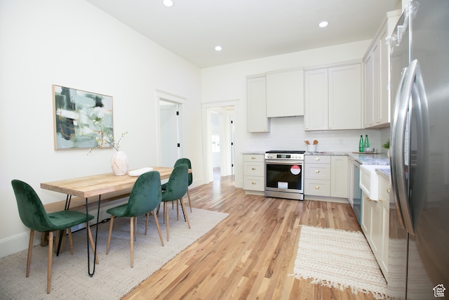 717 E Logan Ave, Salt Lake City, UT 84105 - kitchen featuring backsplash, white cabinetry, appliances with stainless steel finishes, light stone counters, and light hardwood / wood-style floors