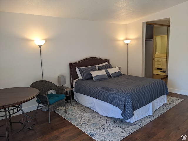 bedroom featuring dark wood-type flooring and ensuite bath