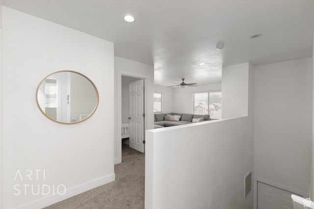 hall with carpet flooring and a textured ceiling