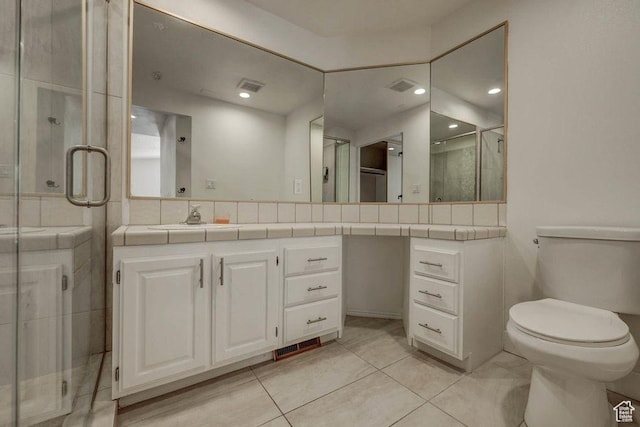 bathroom featuring vanity, toilet, tile patterned floors, and a shower with shower door