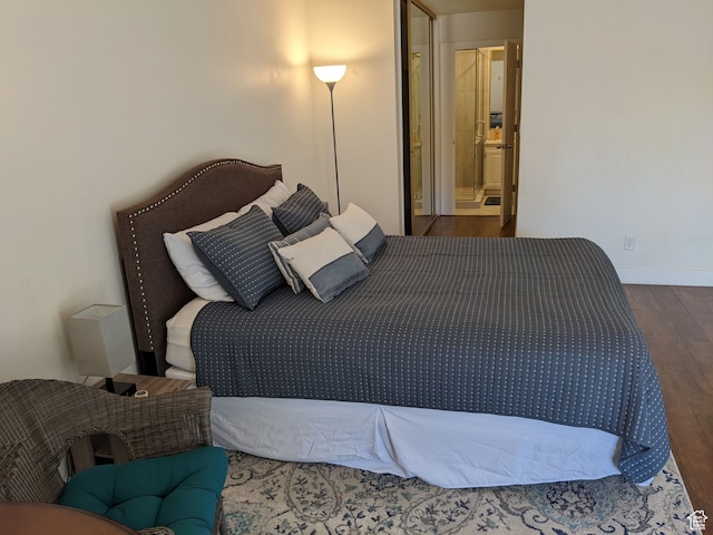 bedroom featuring connected bathroom and dark hardwood / wood-style floors