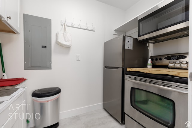 kitchen with appliances with stainless steel finishes, electric panel, white cabinets, and light tile patterned floors