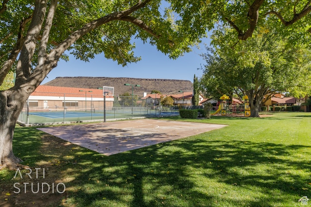 exterior space featuring a lawn, a playground, and basketball hoop