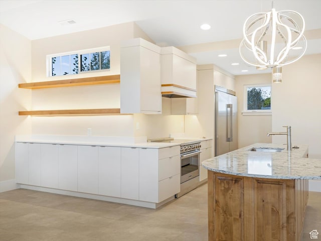 1196 S Liberty Wells Pl, Salt Lake City, UT 84111 - kitchen featuring high end appliances, open shelves, light stone counters, a sink, and an island with sink