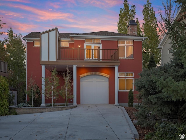 1196 S Liberty Wells Pl, Salt Lake City, UT 84111 - view of front of home with a balcony, concrete driveway, a garage, a chimney, and stucco siding